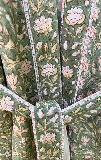 House of Mulmul - Blockprinted Cotton Bathrobe. Close-up of a green floral patterned cotton bathrobe with pink flowers and white stems.