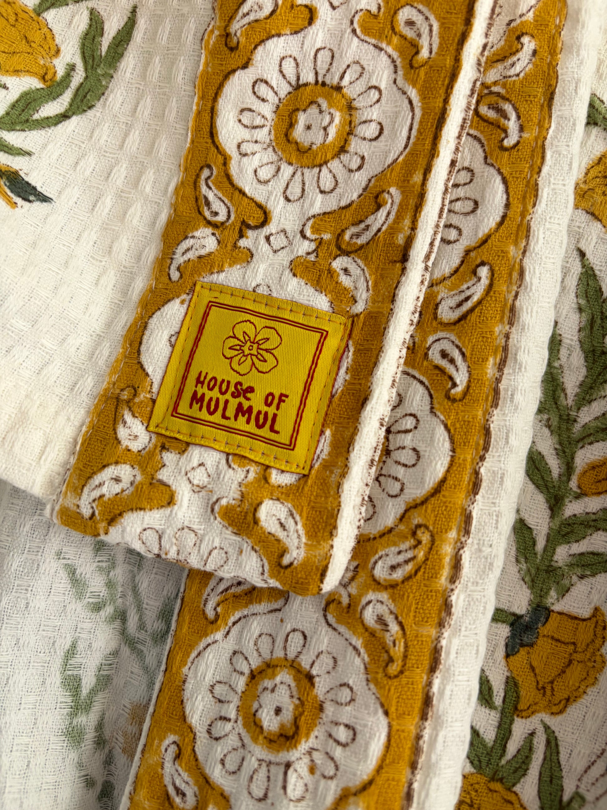 House of Mulmul - Blockprinted Cotton Bathrobe. Close-up of a robe with intricate patterns and 'House of Mulmul' label.