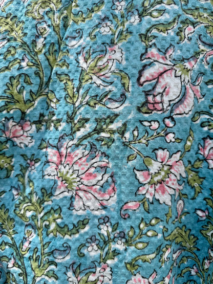 House of Mulmul - Blockprinted Cotton Bathrobe. Close-up of floral patterned cotton bathrobe with pink and green flowers on a blue background