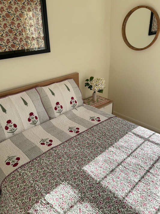House of Mulmul - Blockprinted Muslin Cotton Reversible Bedcover. Indian Blockprint cotton bedcover and quilt. Cotton bedspread and quilt. Handblock printed cotton bedcover and quilt. Bedroom with floral bedspread, pillows, and a mirror on the wall.