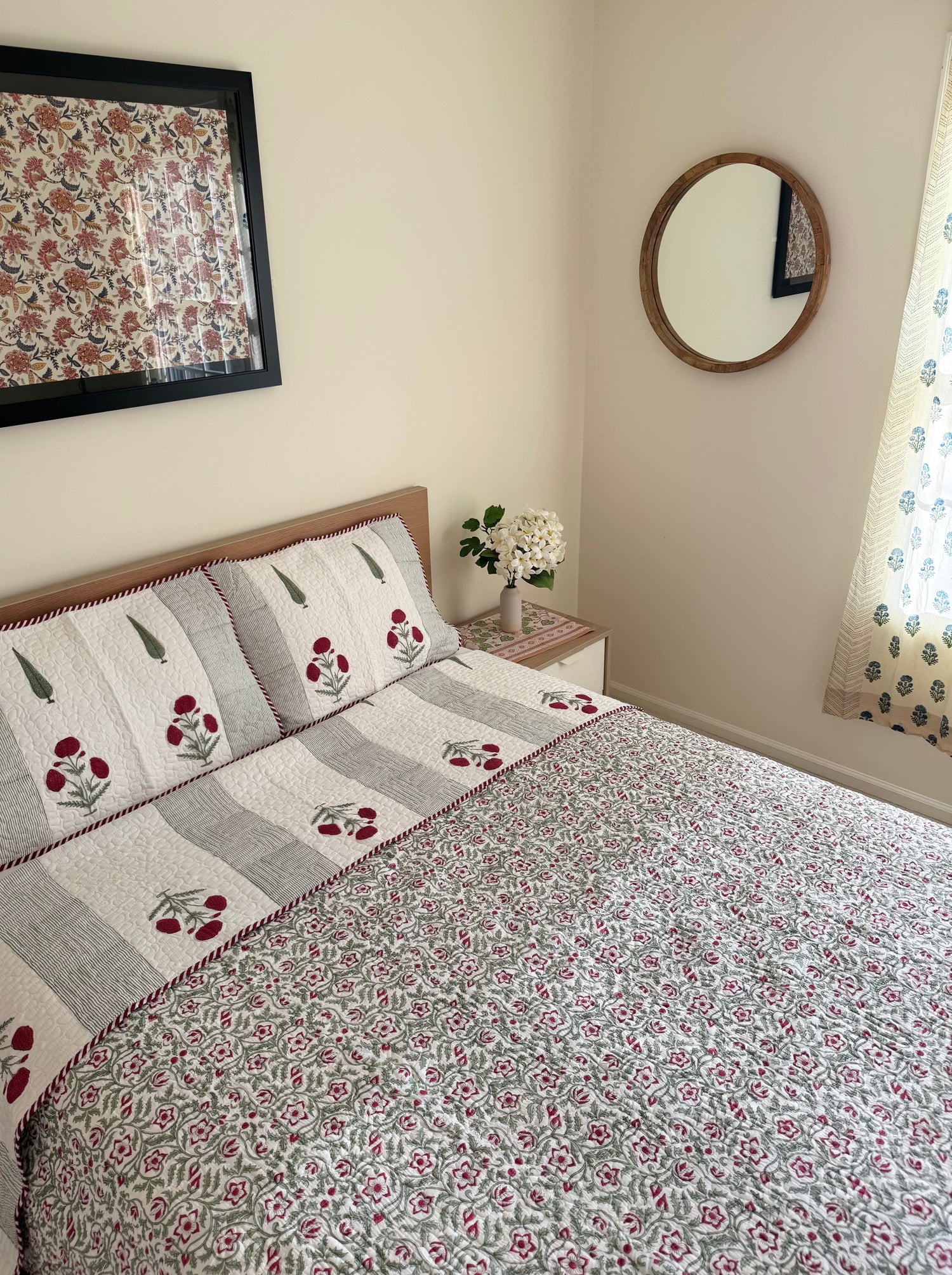 House of Mulmul - Blockprinted Cotton Bedcover Reversible Muslin. Bedroom with floral cotton bedspread, pillows, and decorative elements on a neutral wall.