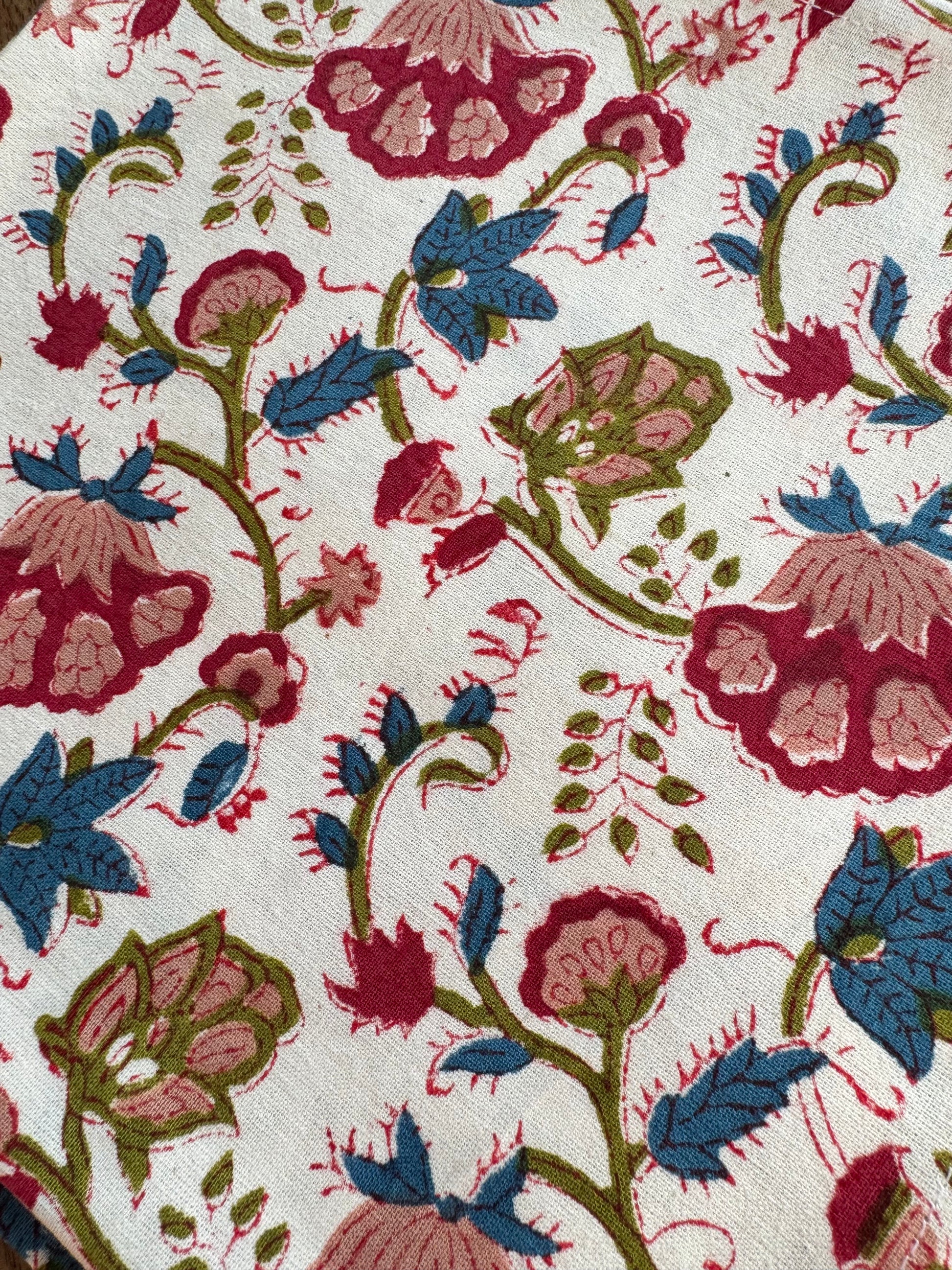 House of Mulmul - Blockprinted Cotton Napkins. Close-up of floral patterned napkins with red, blue, and green colors on a white background.