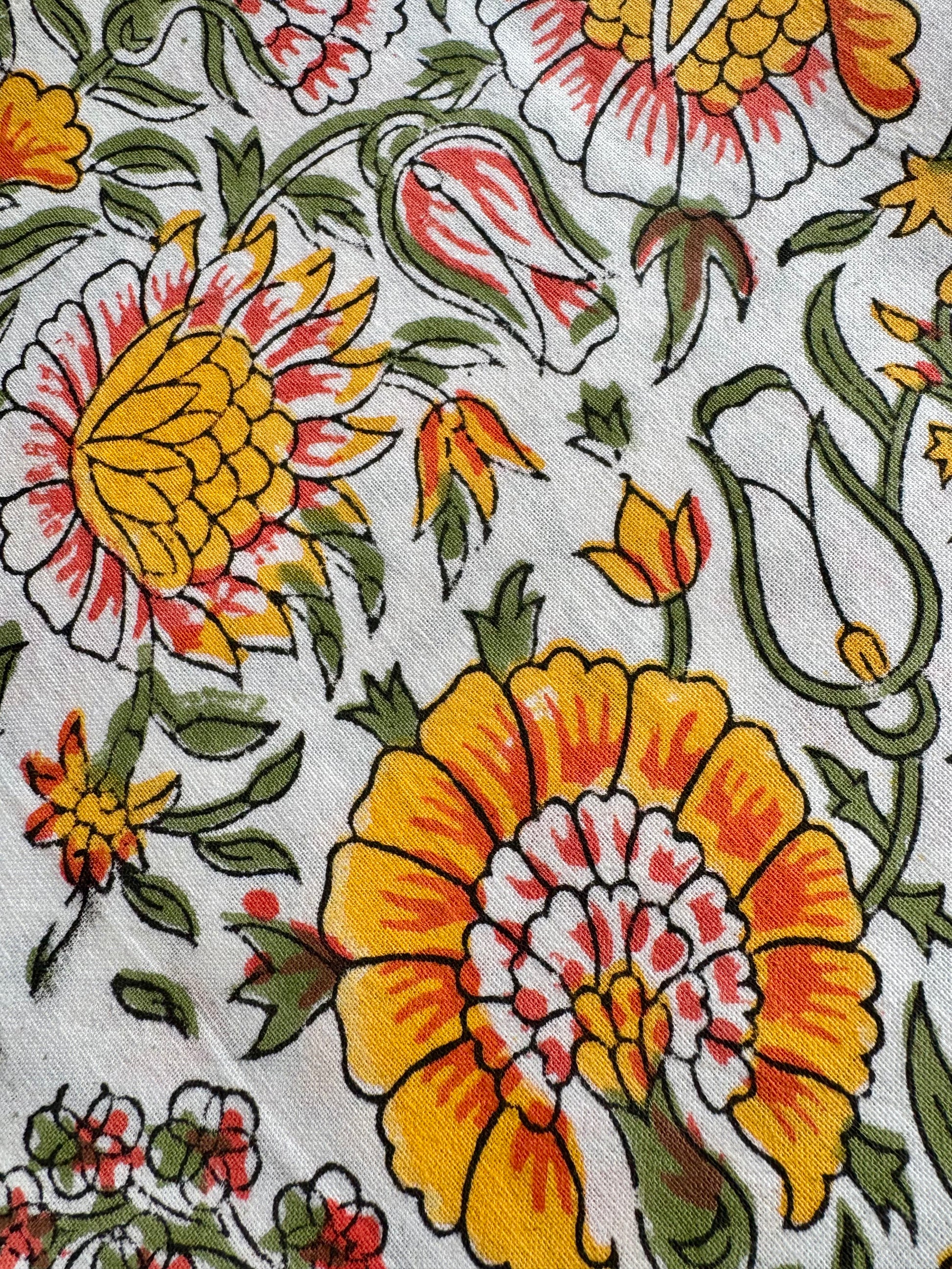 House of Mulmul - Blockprinted Cotton Napkins. Close-up of a floral pattern with orange, yellow, and red flowers on a white background.