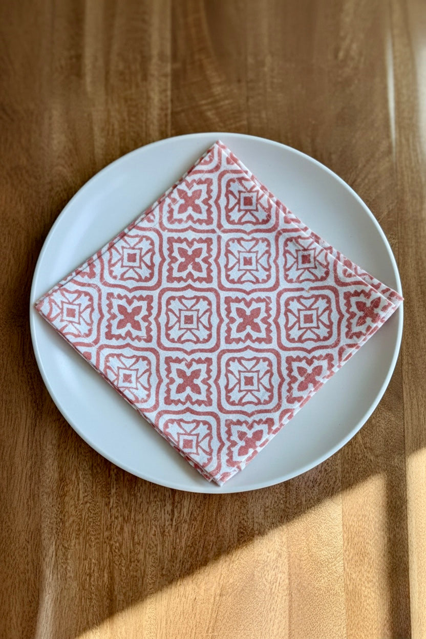 House of Mulmul - Blockprinted Cotton Napkins. Red patterned napkin on a white plate on a wooden table.