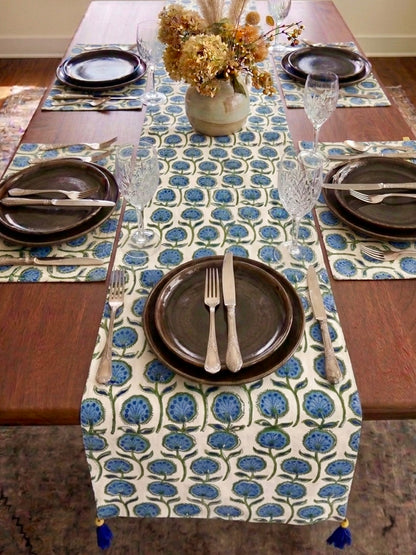 House of Mulmul - Blockprinted Cotton Reversible Table Runner & Mats set. Dining table set with a floral-patterned table runner, plates, and cutlery.