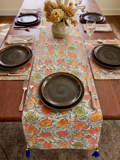 House of Mulmul - Blockprinted Cotton Reversible Table Runner & Mats set. Dining table set with floral table runner, plates, and cutlery on a wooden floor.