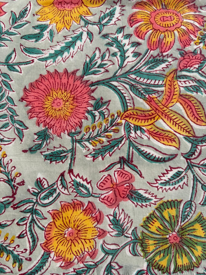 House of Mulmul - Blockprinted Cotton Reversible Table Runner & Mats set. Close-up of floral fabric pattern with pink, yellow, and green colors.