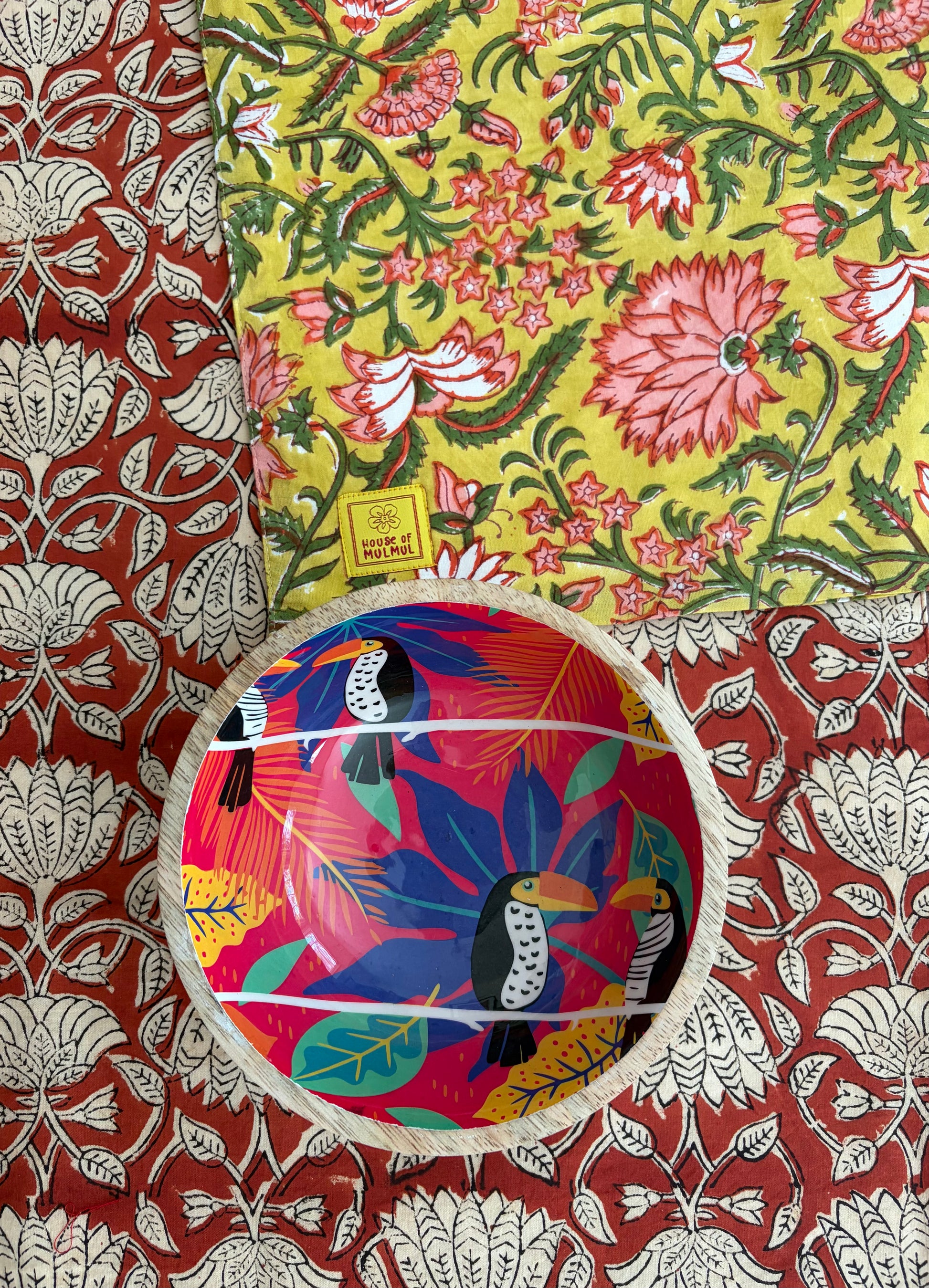 House of Mulmul - Blockprinted Cotton Reversible Table Runner & Mats set. Colorful ceramic bowl with bird design on a floral fabric background