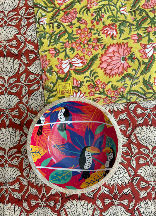 House of Mulmul - Blockprinted Cotton Reversible Table Runner & Mats set. Colorful ceramic bowl with bird design on a floral fabric background