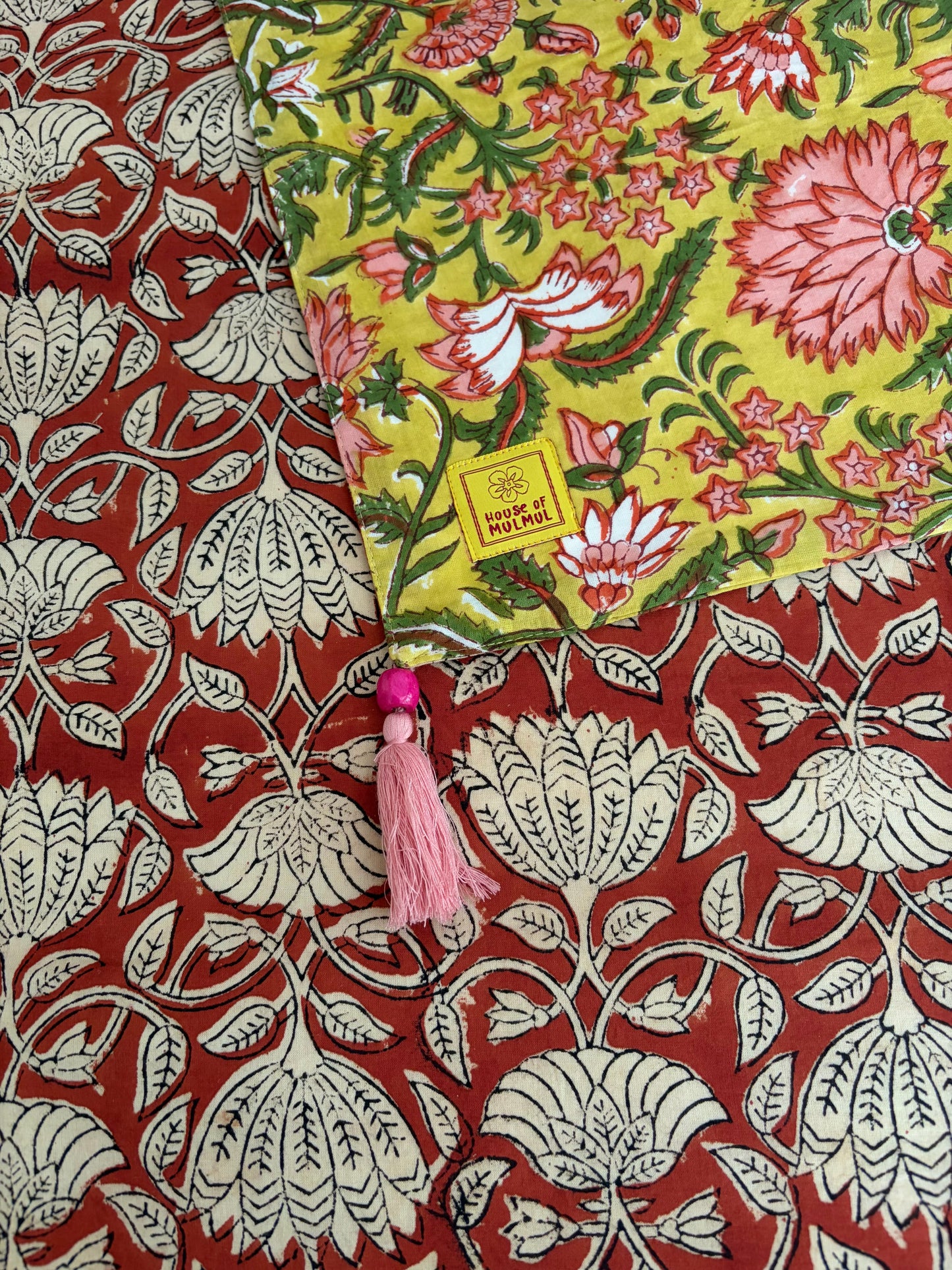 House of Mulmul - Blockprinted Cotton Reversible Table Runner & Mats set. Floral fabric with a tassel on a red and white patterned background