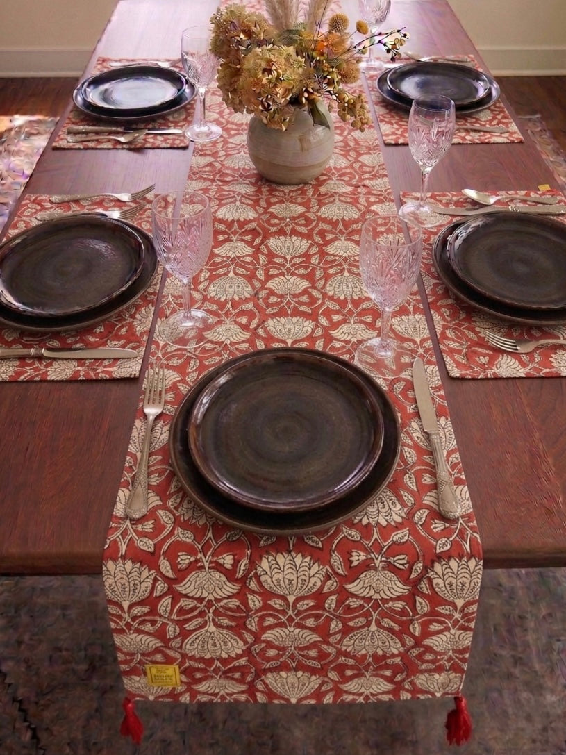 House of Mulmul - Blockprinted Cotton Reversible Table Runner & Mats set. Dining table set with patterned table runner, plates, glasses, and cutlery.