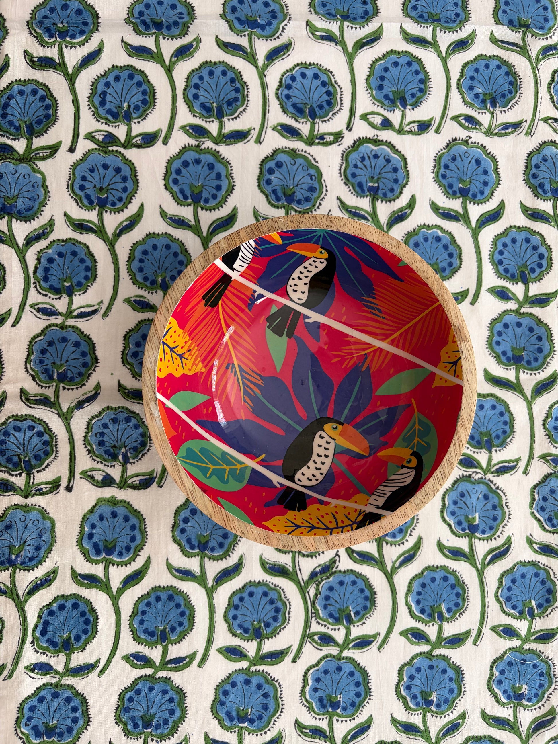 House of Mulmul - Blockprinted Cotton Reversible Table Runner & Mats set. Decorative bowl with colorful design on a floral patterned fabric background