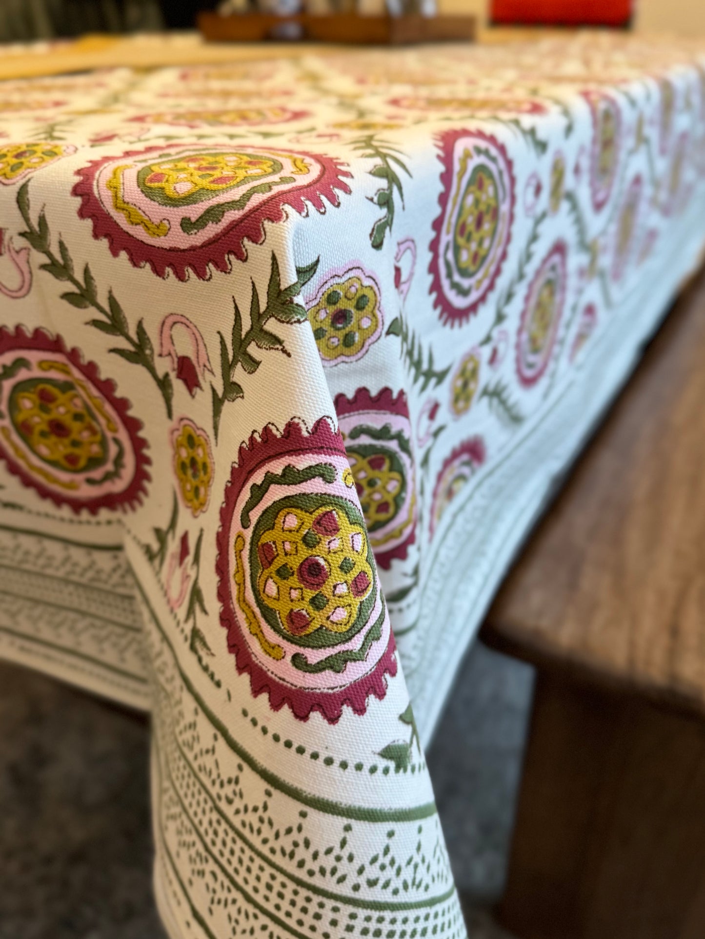 House of Mulmul - Blockprinted Cotton Table Cloth. Close-up of a patterned tablecloth with intricate designs on a wooden surface.