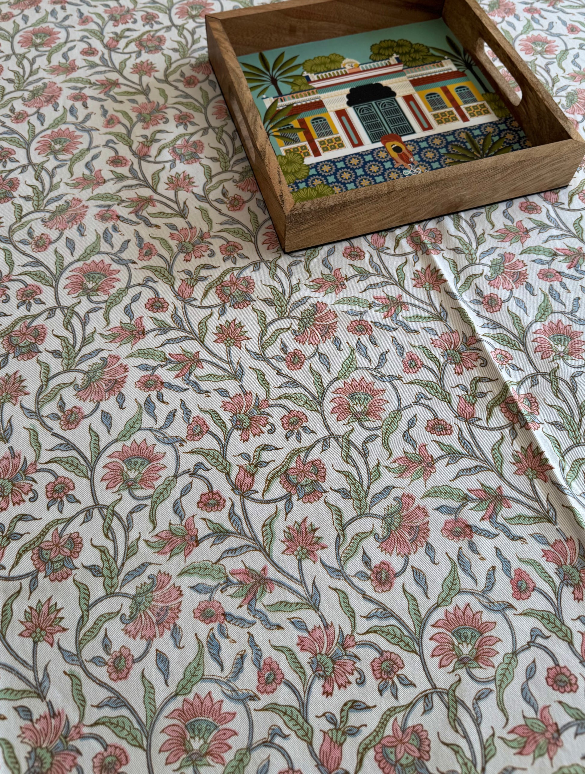 House of Mulmul - Blockprinted Cotton Table Cloth. Floral-patterned table cover with a wooden box containing a colorful painting.