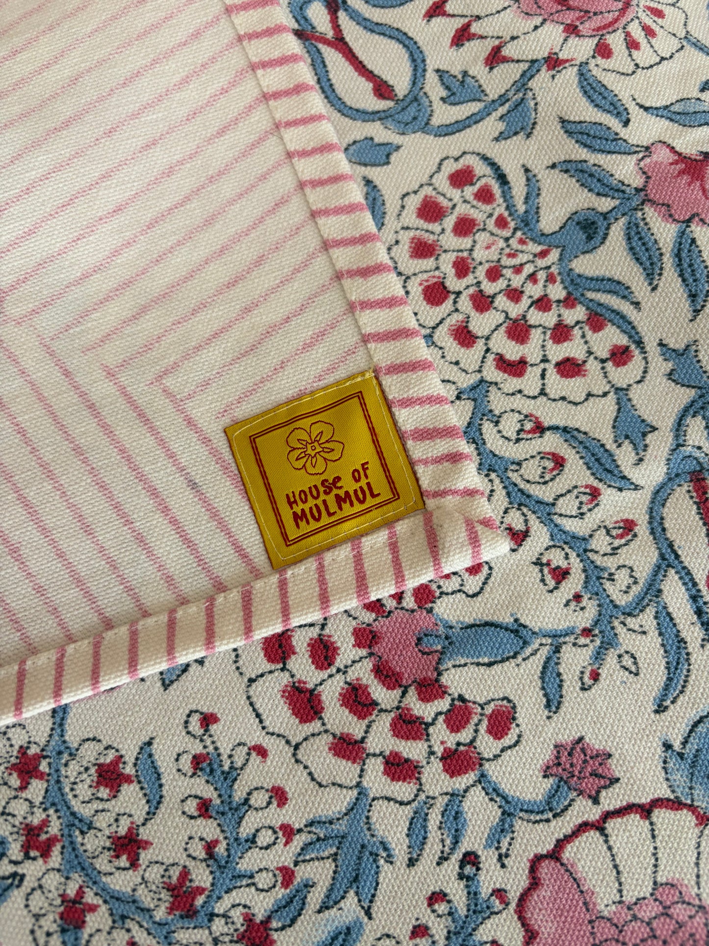 House of Mulmul - Blockprinted Cotton Table Cloth. Close-up of a fabric with floral patterns and a visible House of Mulmul brand label.