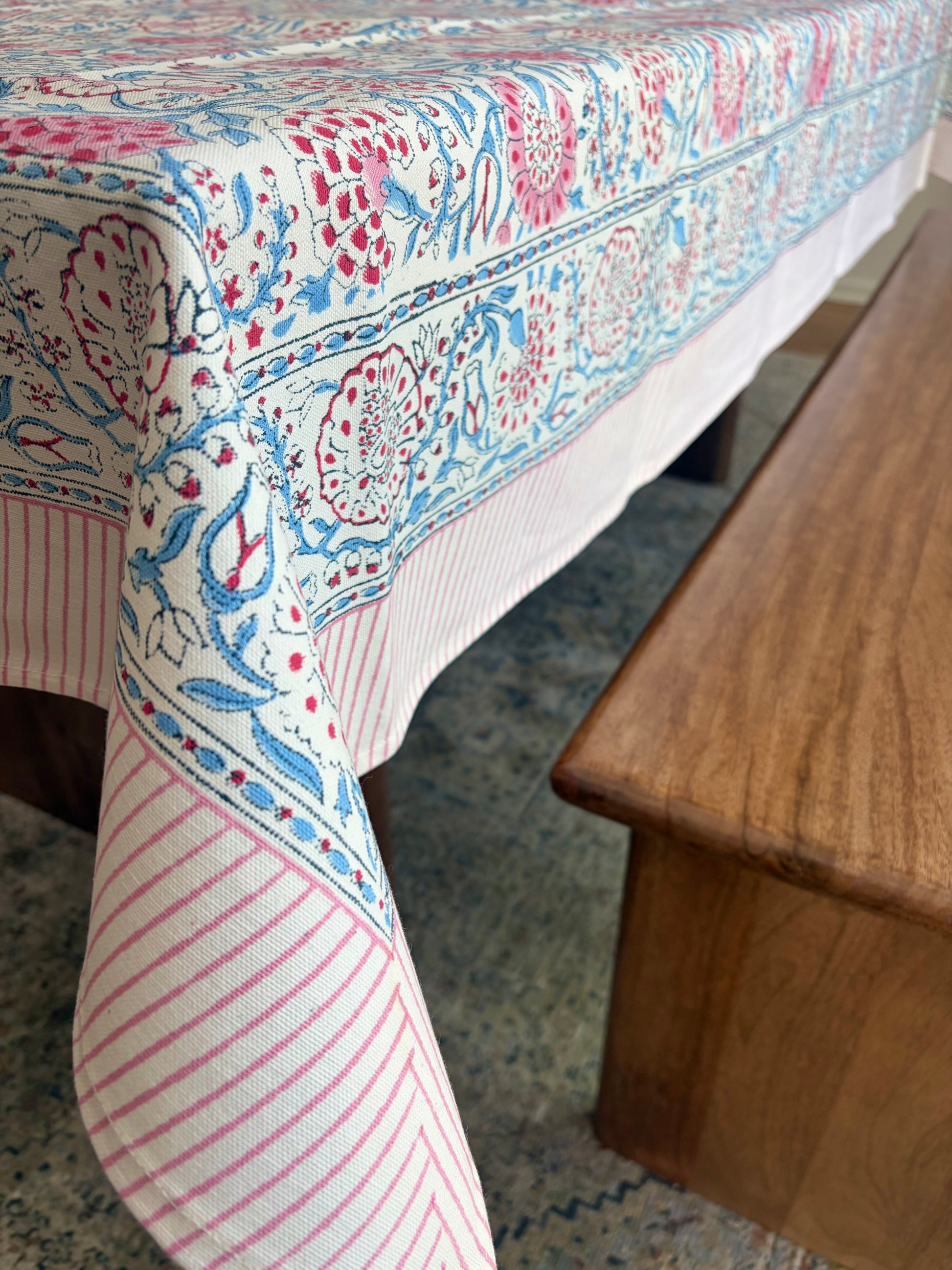 House of Mulmul - Blockprinted Cotton Table Cloth. Patterned tablecloth on a wooden table with a blurred background