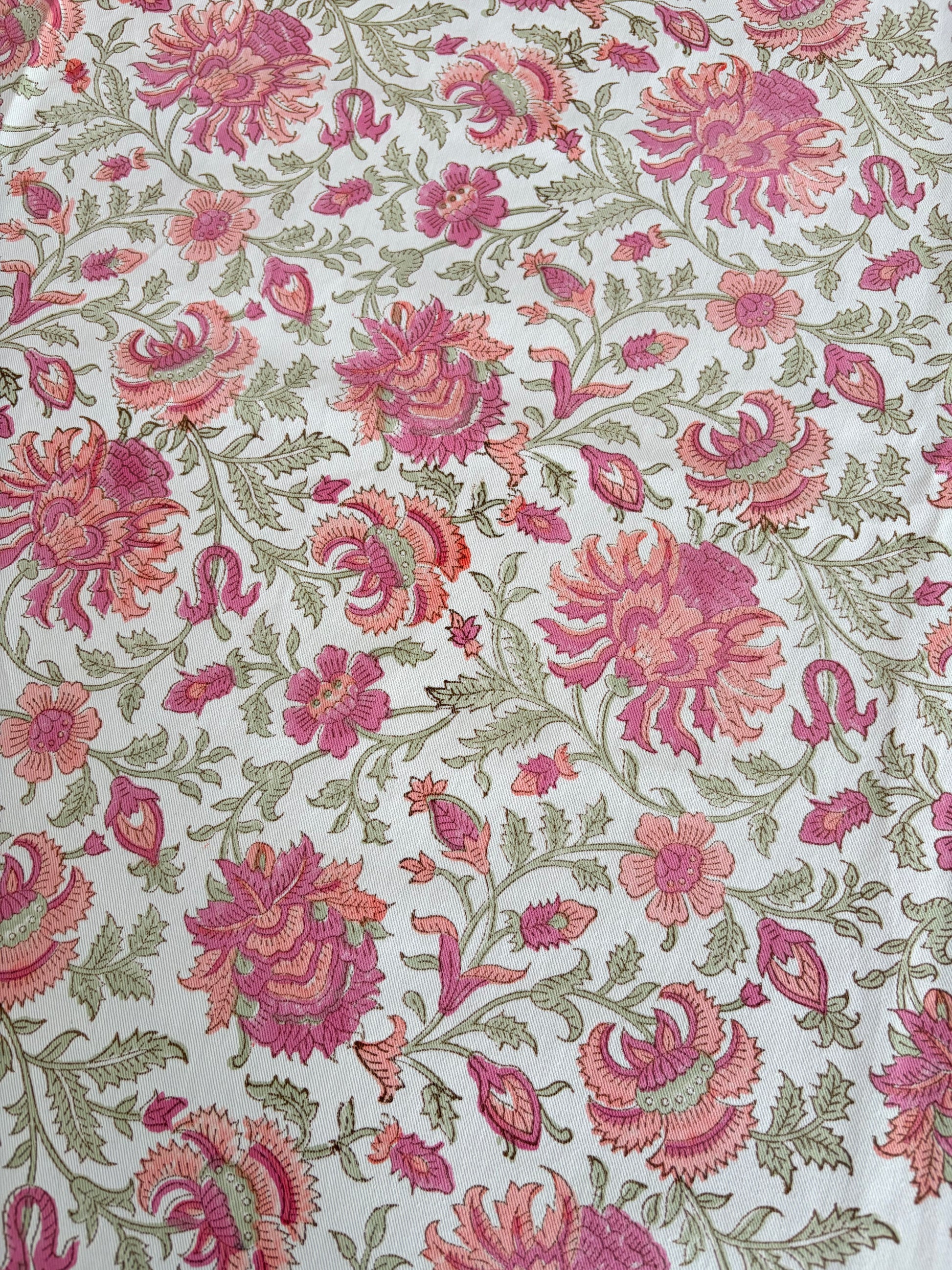 House of Mulmul - Blockprinted Cotton Table Cloth. A close-up of a floral fabric pattern featuring pink and magenta flowers with green leaves on a white background.