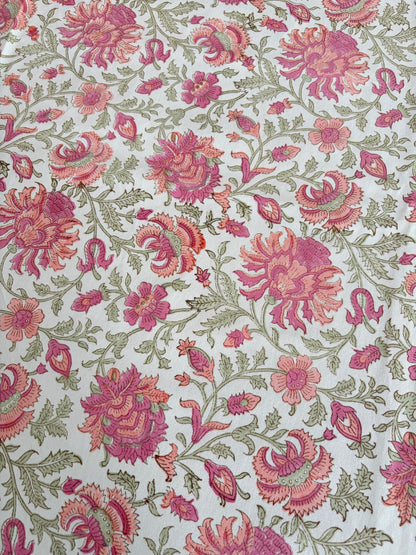 House of Mulmul - Blockprinted Cotton Table Cloth. A close-up of a floral fabric pattern featuring pink and magenta flowers with green leaves on a white background.