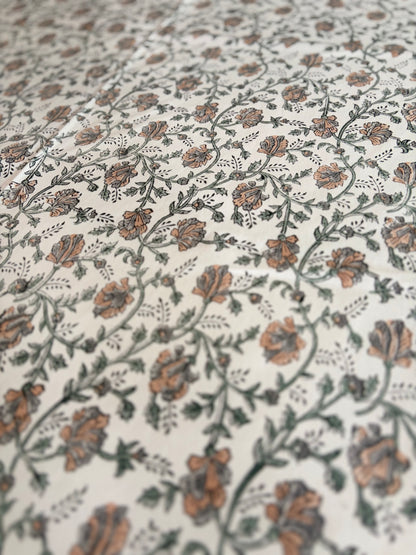 House of Mulmul - Blockprinted Cotton Table Cloth. A close-up of a fabric or wallpaper pattern featuring delicate floral vines in muted terracotta orange, olive green, and gray on an off-white background.