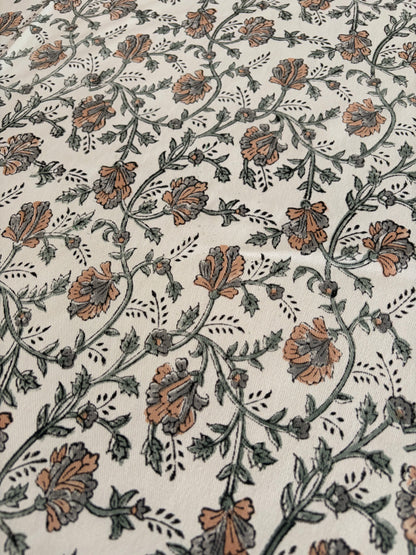House of Mulmul - Blockprinted Cotton Table Cloth. A close-up of a fabric or wallpaper pattern featuring a repeating floral vine design in muted brown and gray on an off-white background.