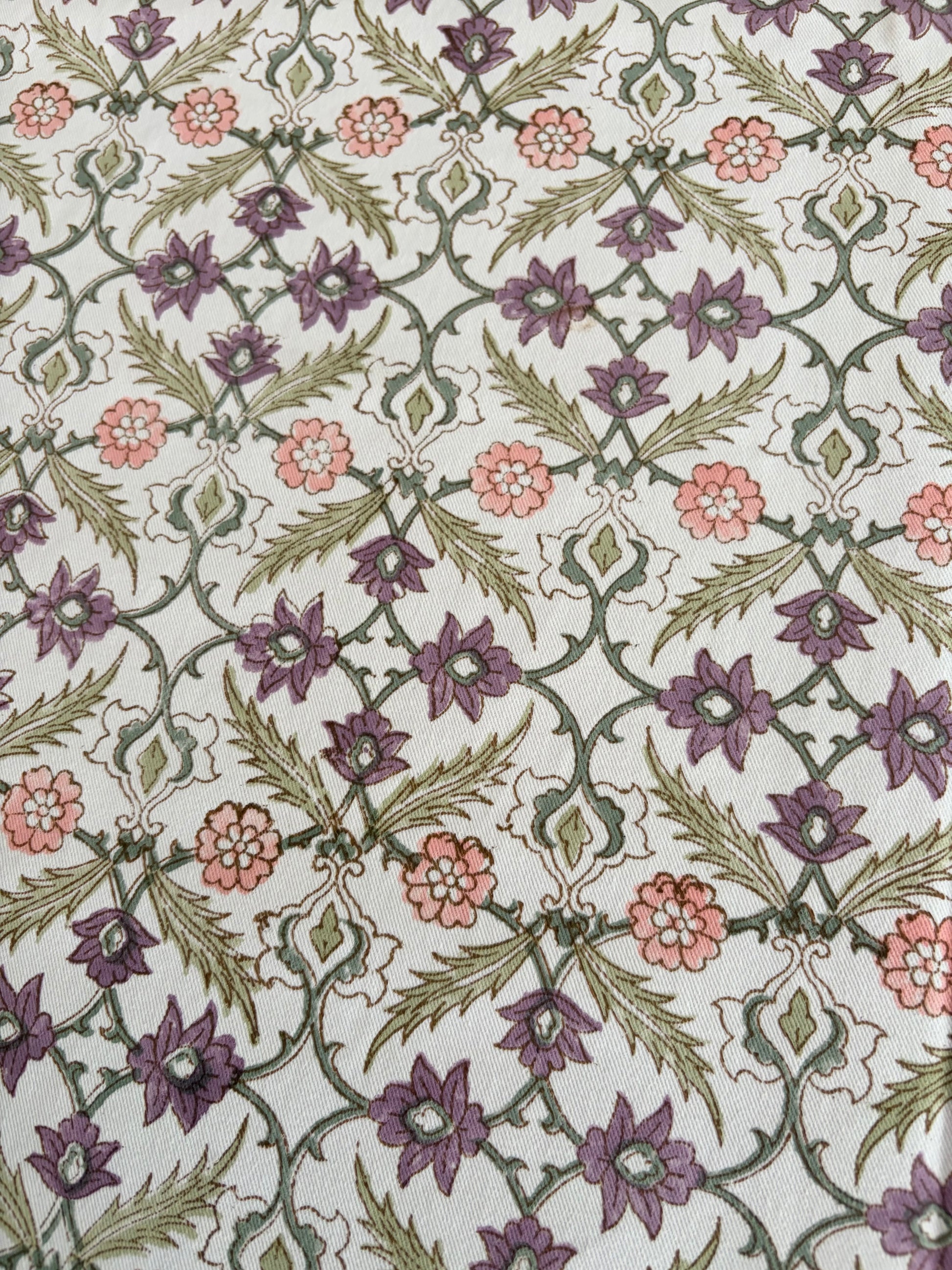 House of Mulmul - Blockprinted Cotton Table Cloth. A close-up of a patterned textile or rug featuring a repeating floral and vine motif in muted purple, dusty pink, olive green, and cream.