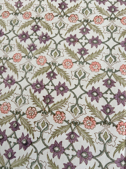 House of Mulmul - Blockprinted Cotton Table Cloth. A close-up of a patterned textile or rug featuring a repeating floral and vine motif in muted purple, dusty pink, olive green, and cream.