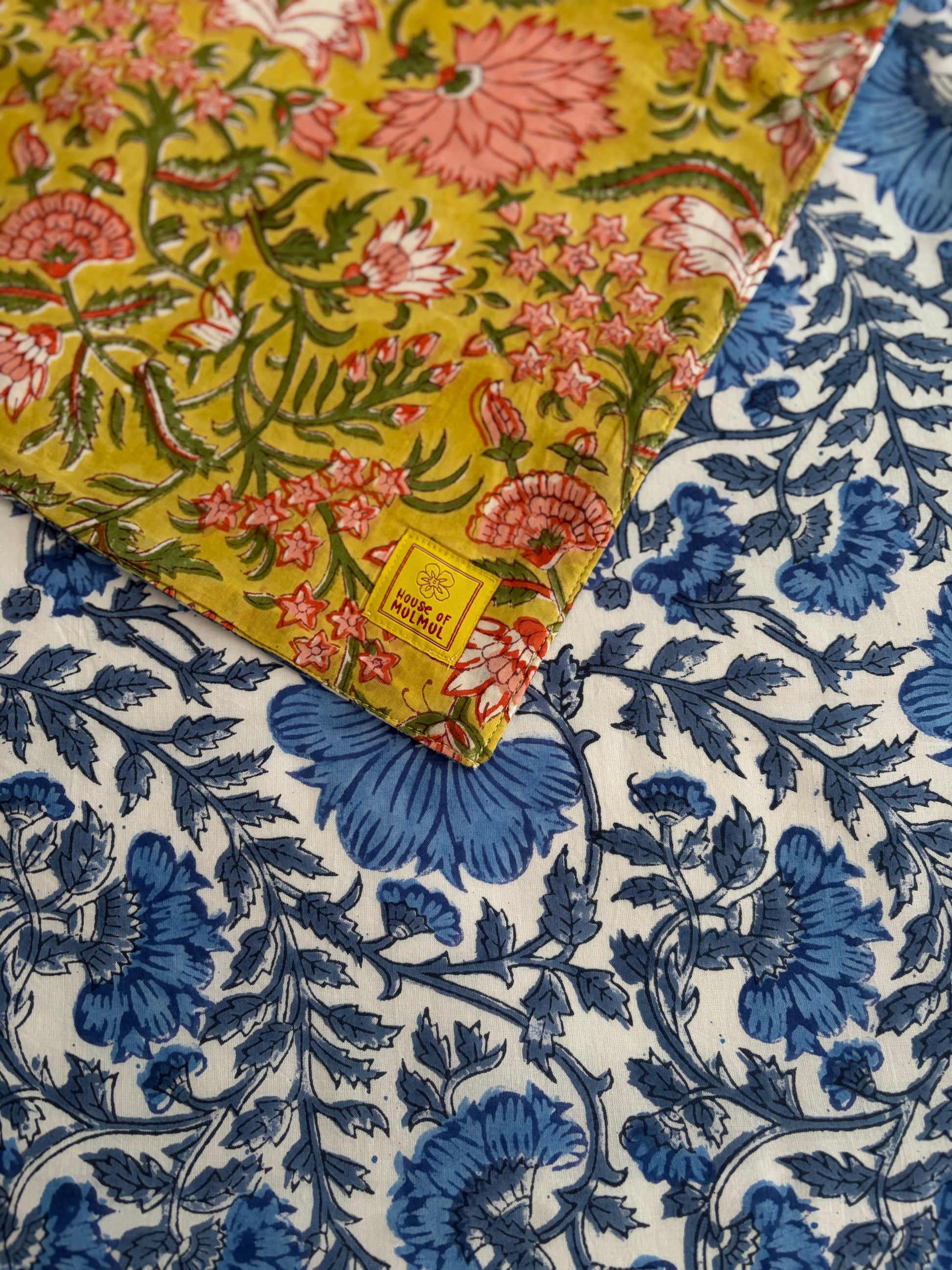 House of Mulmul - Blockprinted Cotton Reversible Table Runner & Placemats set. Close-up of floral fabric with yellow, blue, and white patterns.