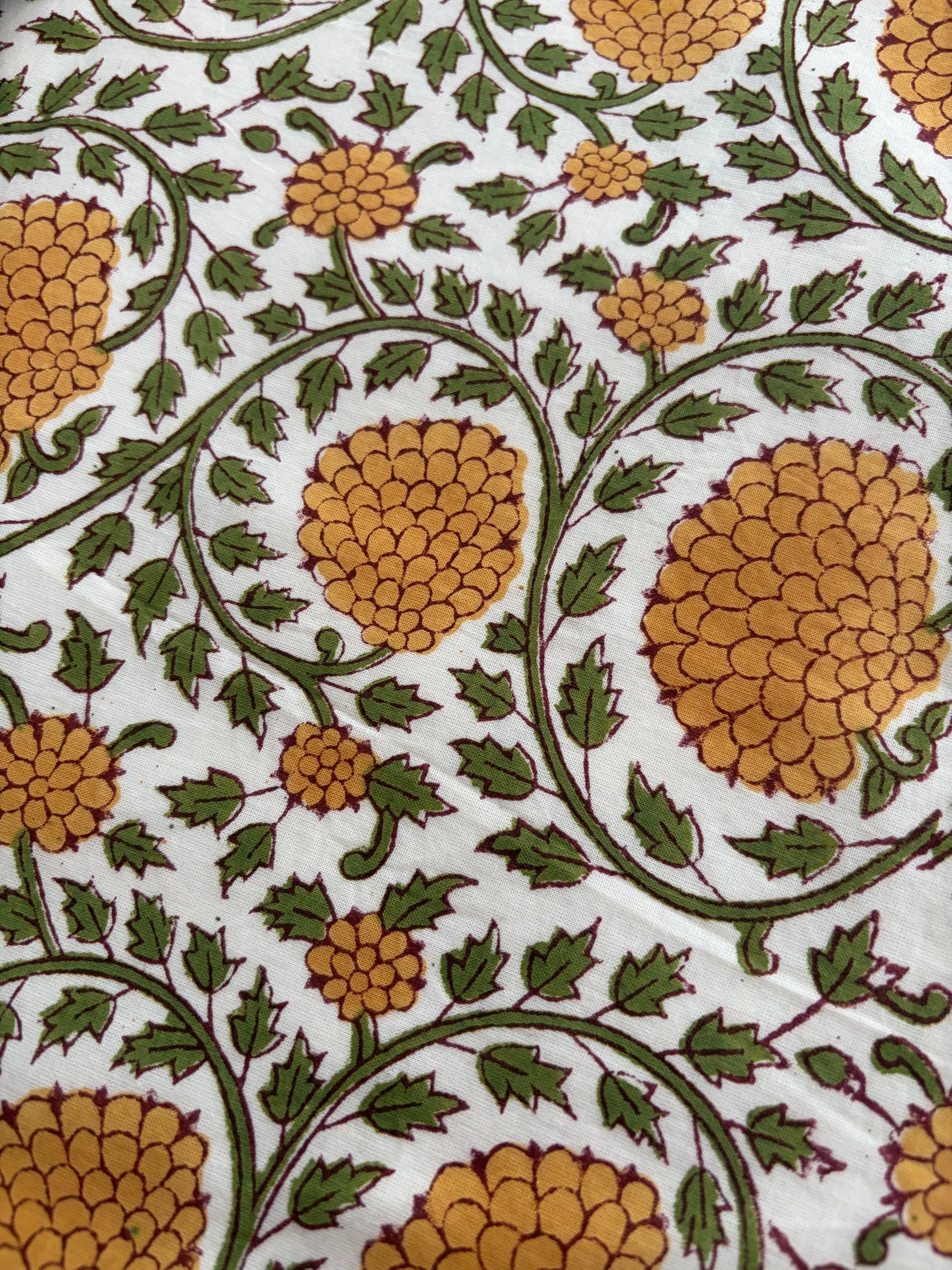 House of Mulmul - Blockprinted Cotton Reversible Table Runner & Placemats set. Close-up of a floral pattern with yellow flowers and green leaves on a white background