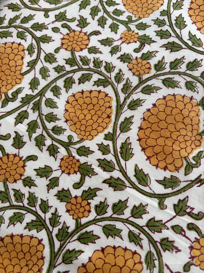 House of Mulmul - Blockprinted Cotton Reversible Table Runner & Placemats set. Close-up of a floral pattern with yellow flowers and green leaves on a white background