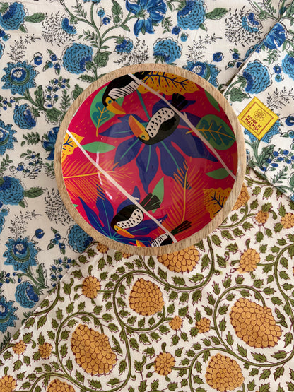 House of Mulmul - Blockprinted Cotton Reversible Table Runner & Placemats set. Decorative plate with colorful bird design on a floral patterned surface