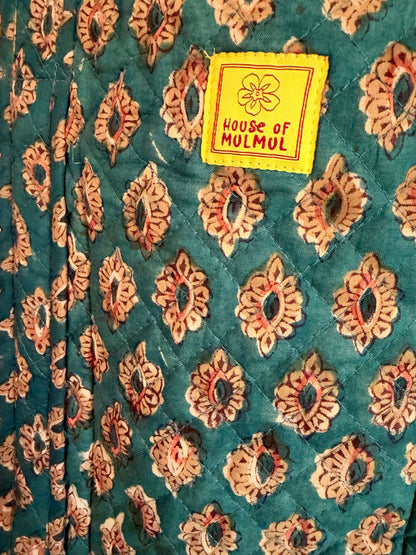 House of Mulmul - Blockprinted Cotton Tote Bags. Close-up of a quilted fabric with a teal green background and a repeating floral block print in beige and rust red. A yellow sewn-in label reads 'HOUSE OF MULMUL'.