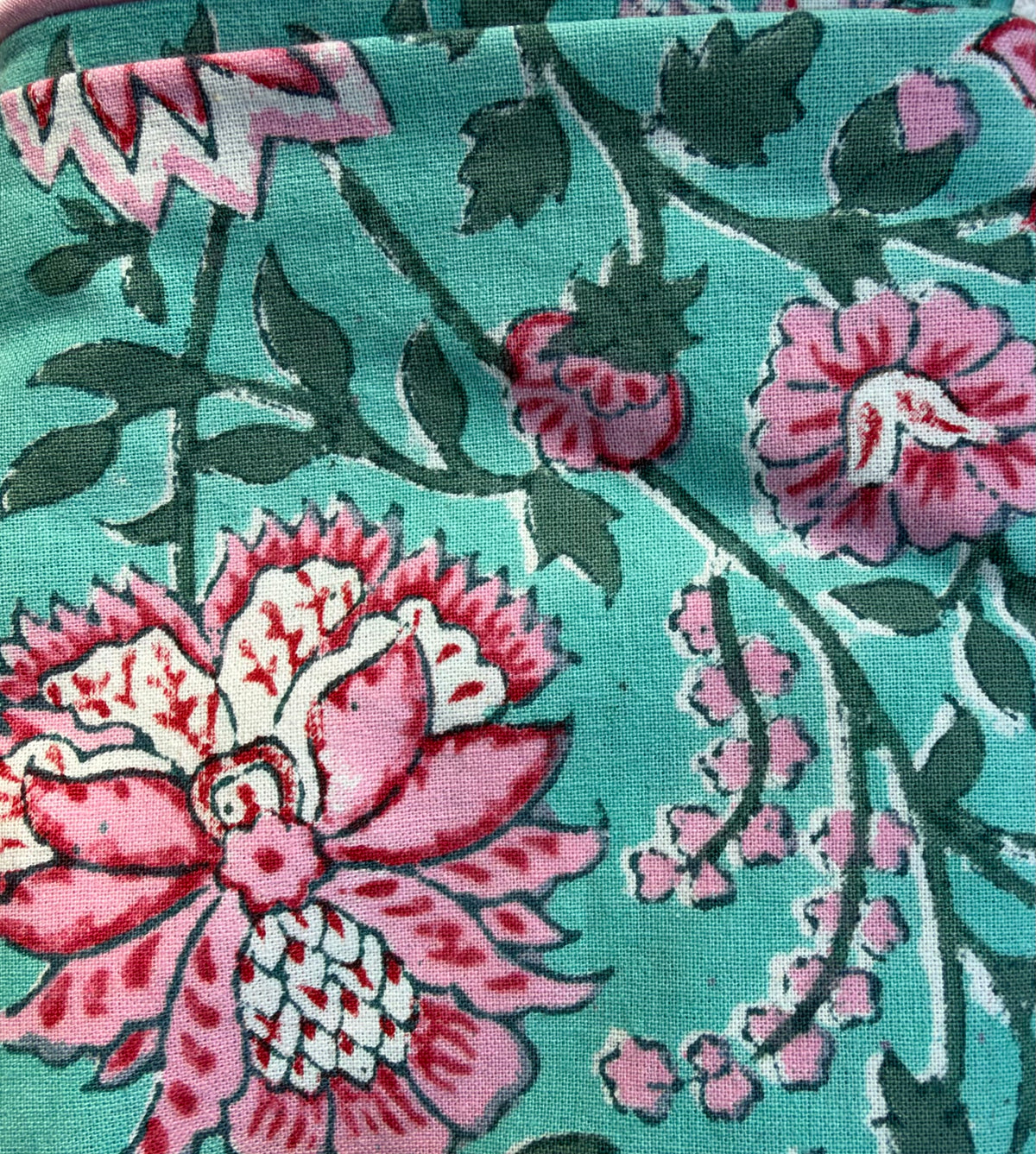 House of Mulmul - Blockprinted Cushion Covers-Pillow Cases. A close-up of a printed textile or fabric pattern featuring large pink and white flowers, smaller pink buds, and dark green leaves on a turquoise background.