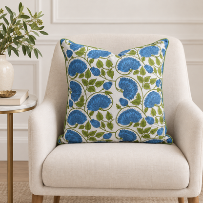 House of Mulmul - Blockprinted Cushion Covers-Pillow Cases. A square throw pillow with a blue and green floral pattern on a white background, styled on a light beige armchair next to a side table with a plant.
