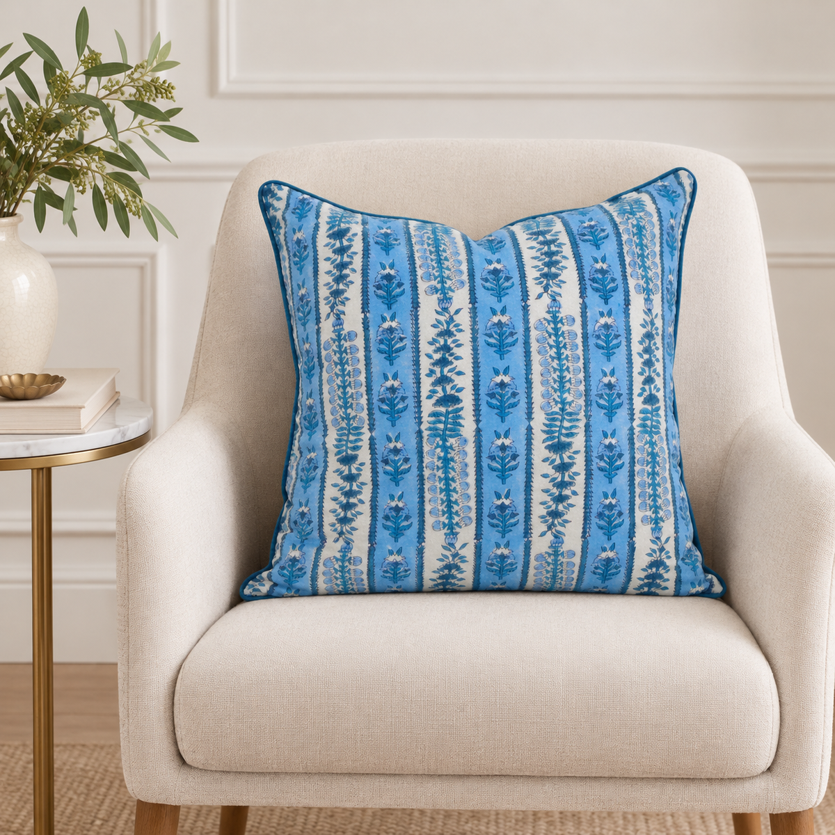 House of Mulmul - Blockprinted Cushion Covers-Pillow Cases. A square throw pillow with a blue and white vertical floral pattern, resting on a beige upholstered armchair in a styled room setting.
