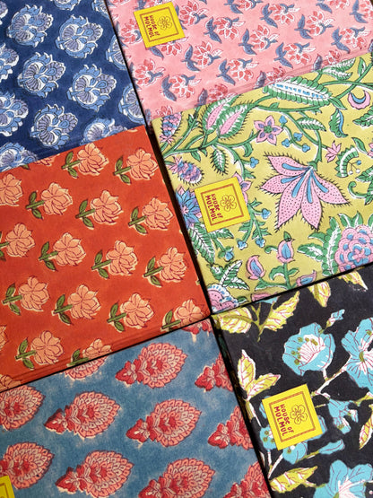 House of Mulmul - Blockprinted Journal Diary Notebook. Six patterned notebooks arranged in a grid, each with a different floral and botanical print in colors including blue, pink, orange, yellow, and black. Each sheet has a small yellow square label with text.