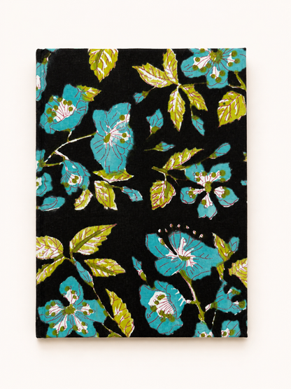 House of Mulmul - Blockprinted Journal Diary Notebook. A rectangular black notebook or journal with a vibrant floral pattern featuring turquoise blue flowers and olive green leaves, displayed flat against a light beige background.
