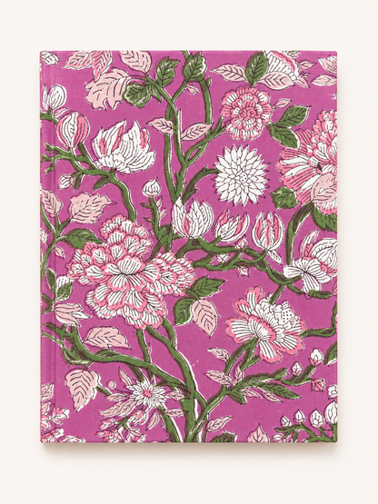 House of Mulmul - Blockprinted Journal Diary Notebook. A hardcover notebook with a vibrant magenta floral pattern featuring pink, white, and green blossoms and leaves, displayed flat against a light cream background.