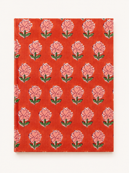 House of Mulmul - Blockprinted Journal Diary Notebook. A hardcover notebook with a vibrant orange-red cover featuring a repeating block-print style floral pattern of pink flowers with green leaves, shown against a plain off-white background.