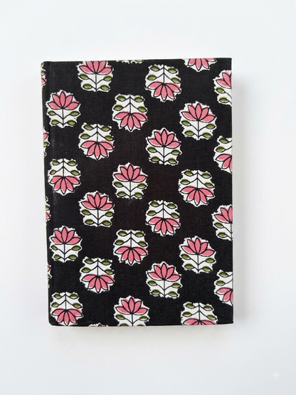 House of Mulmul - Blockprinted Journal Diary Notebook. A hardcover notebook with a black cover decorated with a repeating pink, white, and green block print floral pattern, shown against a plain white background.