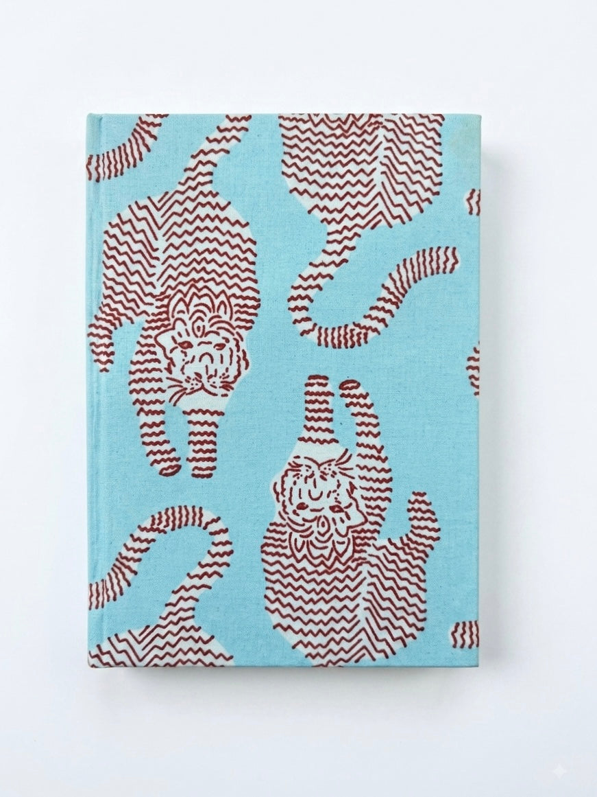 House of Mulmul - Blockprinted Journal Diary Notebook. A hardcover notebook with a light blue cover featuring a pattern of stylized cats in reddish-brown with wavy stripes, shown against a plain white background.
