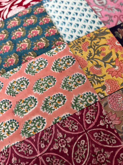 House of Mulmul - Blockprinted Journal Diary Notebook. A close-up of a patchwork quilt made of multiple colorful block-print cotton fabrics with traditional floral and geometric patterns.