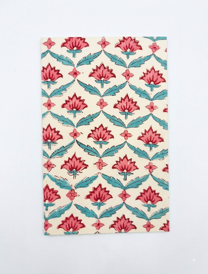 House of Mulmul - Blockprinted Journal Diary Notebook. A rectangular notebook, featuring a repeating block-print style floral pattern with pink lotus flowers and teal leaves on a cream background, shown flat against a light gray backdrop.