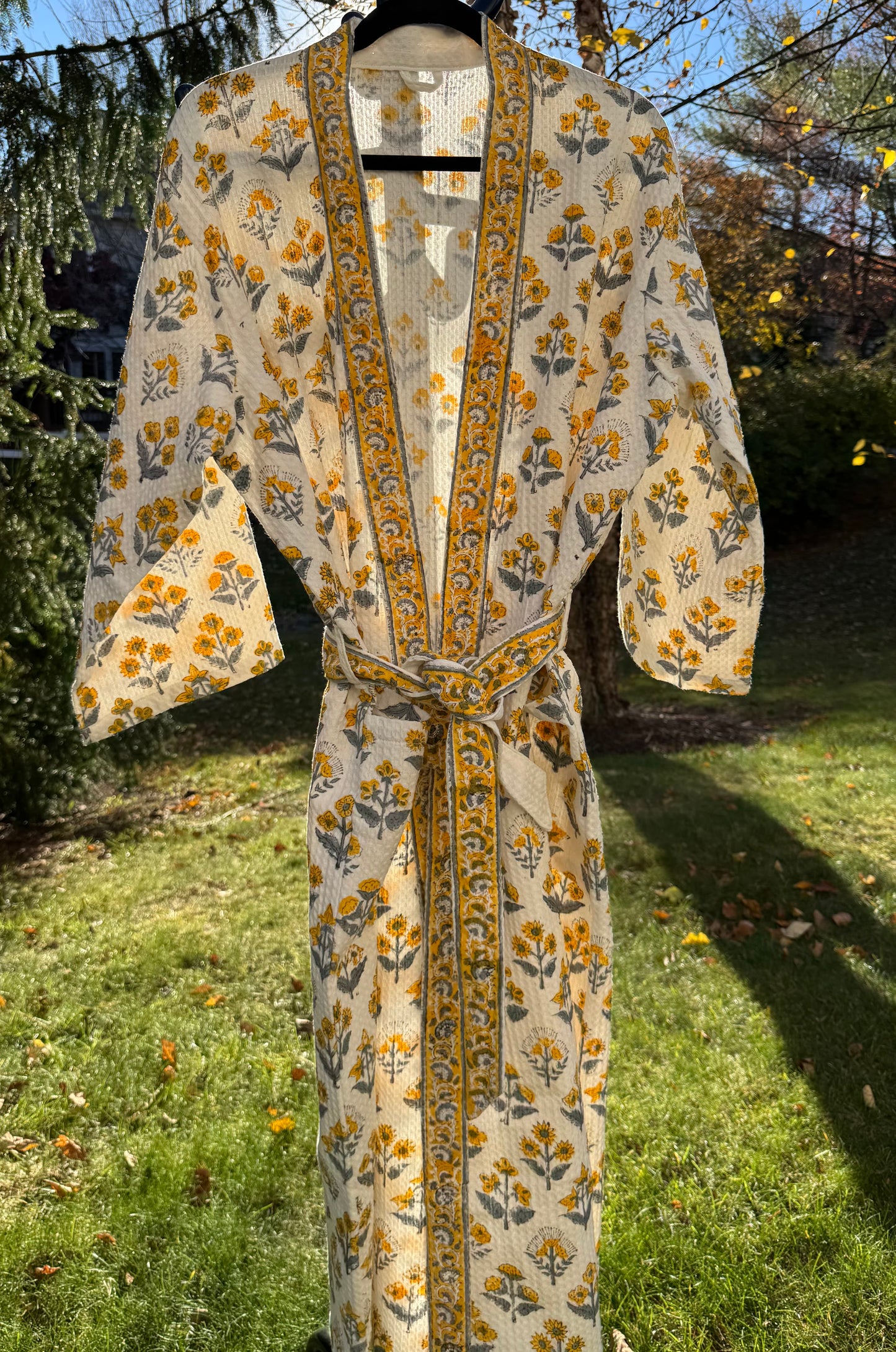 House of Mulmul - Cotton Bath robe. Floral-patterned robe hanging outdoors on a sunny day