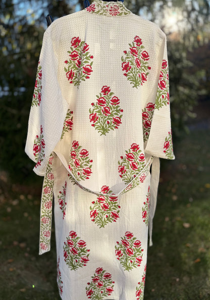 House of Mulmul - Cotton Bath robe. White bathrobe with red and green floral patterns on a blurred natural background