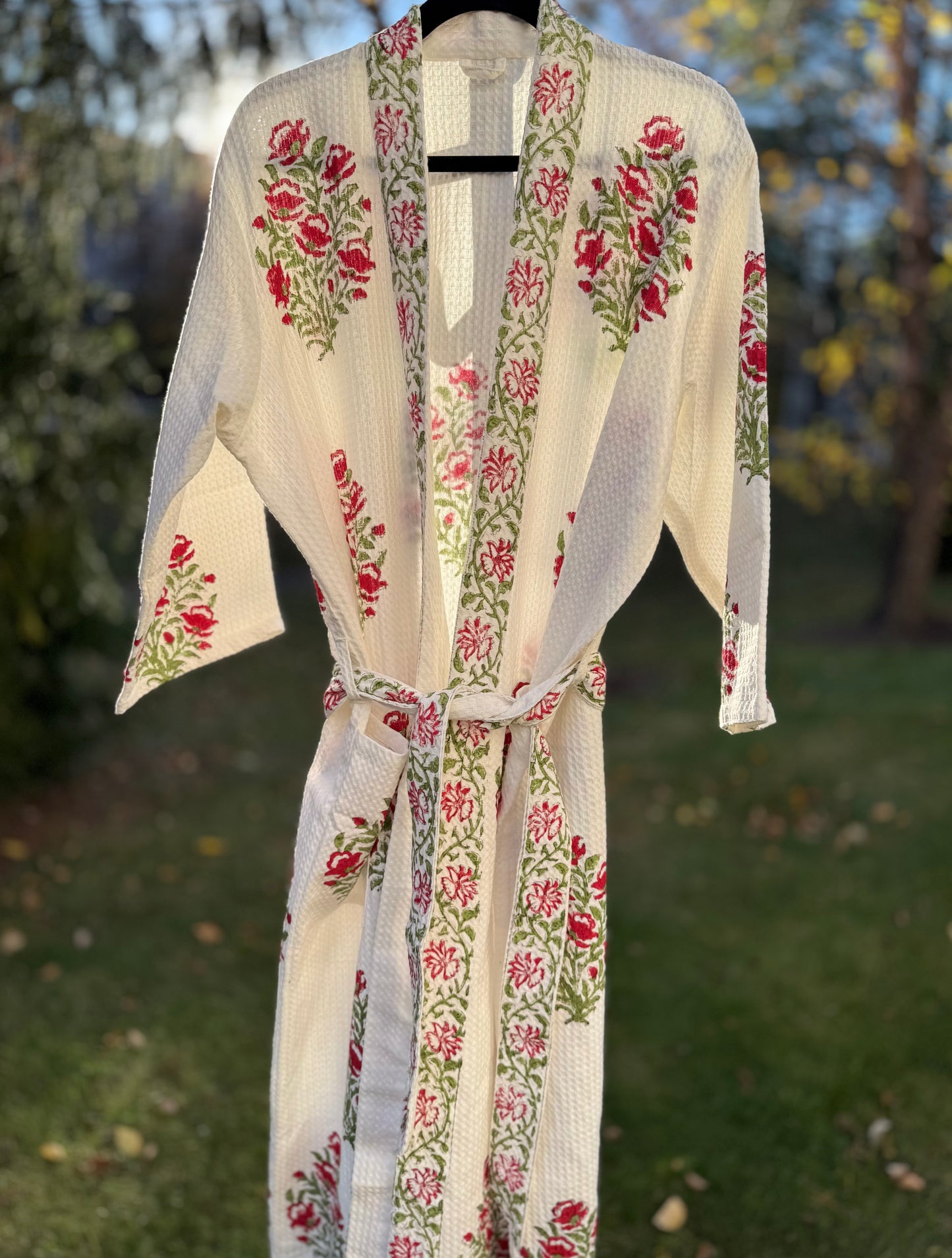 House of Mulmul - Cotton Bath robe. Floral embroidered robe on a hanger with a blurred natural background