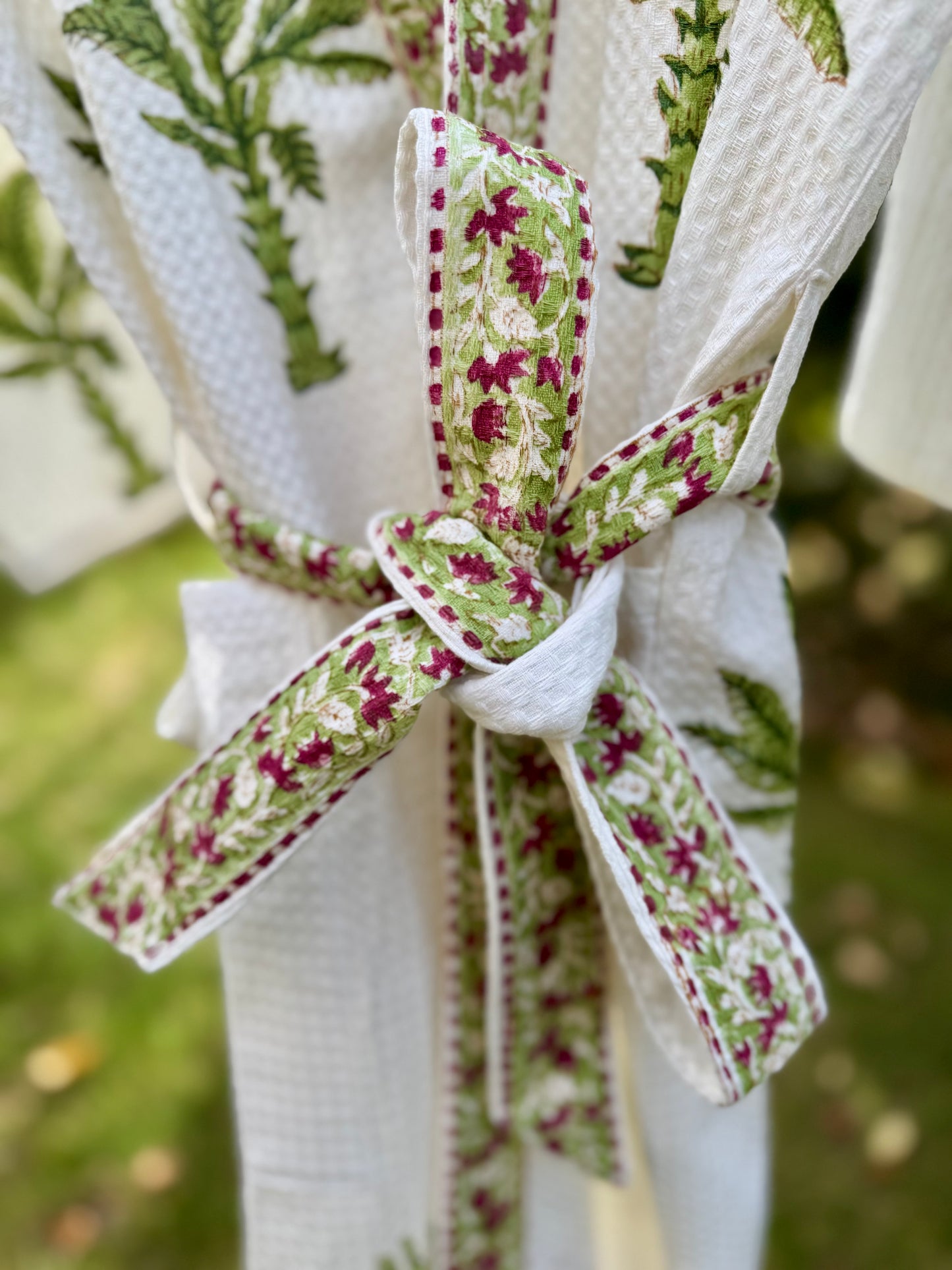 House of Mulmul - Cotton Bath robe. White embroidered robe with green and red floral ribbon tied around it.