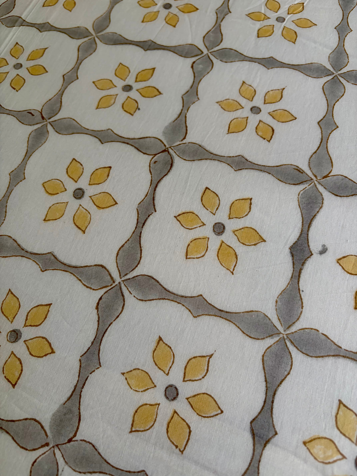 House of Mulmul - Handblock printed cotton summer quilt. Cotton coverlet. Cotton dohar. Muslin blanket. Indian summer quilt. Indian dohar. A close-up of a patterned textile featuring a repeating geometric grid with yellow flower motifs and gray curved lines on an off-white background.