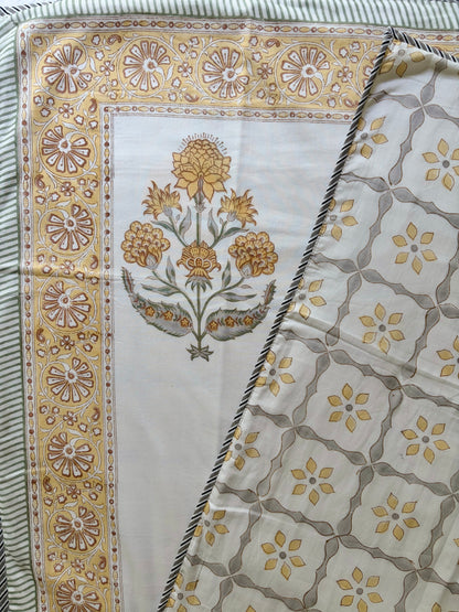 House of Mulmul - Handblock printed cotton summer quilt. Cotton coverlet. Cotton dohar. Muslin blanket. Indian summer quilt. Indian dohar. A folded patterned textile, likely a scarf or shawl, showing a cream base with a yellow and brown floral motif on one side and a repeating yellow and brown geometric lattice pattern on the other, bordered by a striped edge.