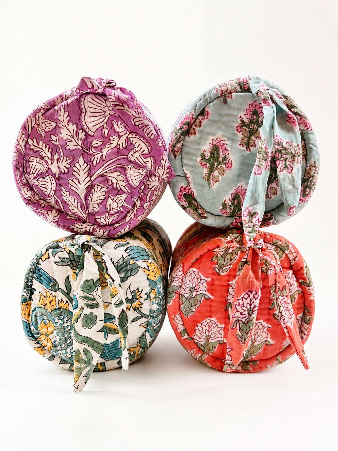 House of Mulmul - Cotton Quilted Makeup-Pencil Pouch. Four round quilted fabric pouches with tie closures, arranged in a 2x2 stack on a white background. Each pouch features a different floral and botanical block-print pattern in vibrant colors including purple, sage green, teal, and coral red.