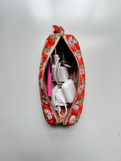 House of Mulmul - Cotton Quilted Makeup Barrel Pouch. A red floral zippered pouch shown open from a top-down view, filled with white cables and a pink item, on a plain light gray background.